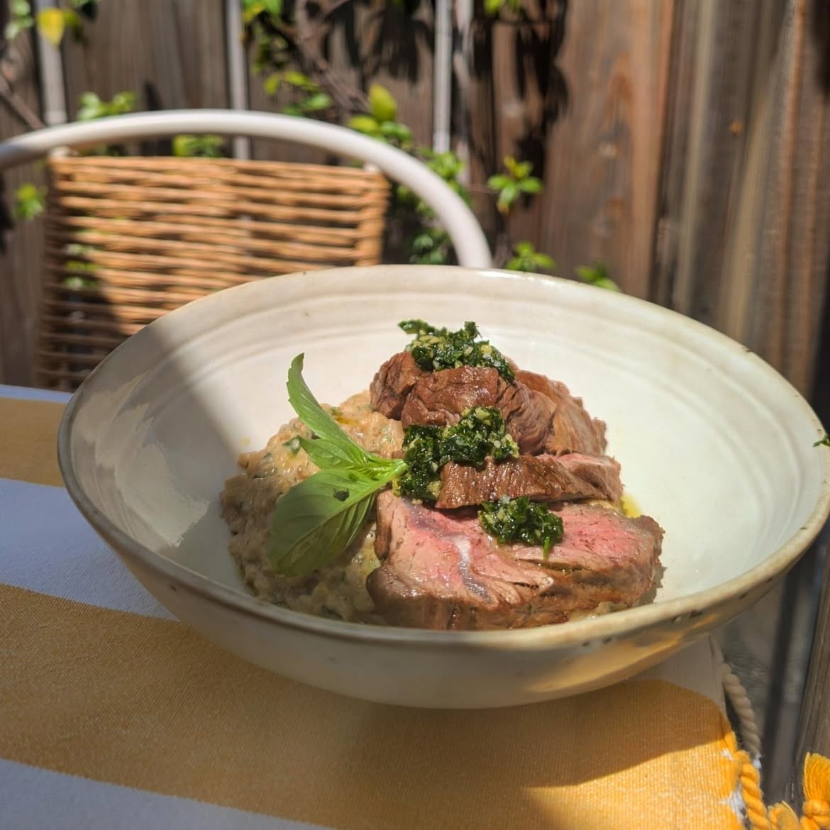 Tranches de bœuf rosé sauce chimichurri sur lit de risotto, herbes fraîches