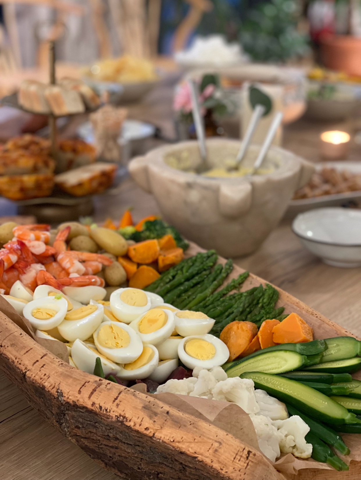 Grand plateau en bois avec œufs durs, crevettes, asperges, légumes variés et chou-fleur