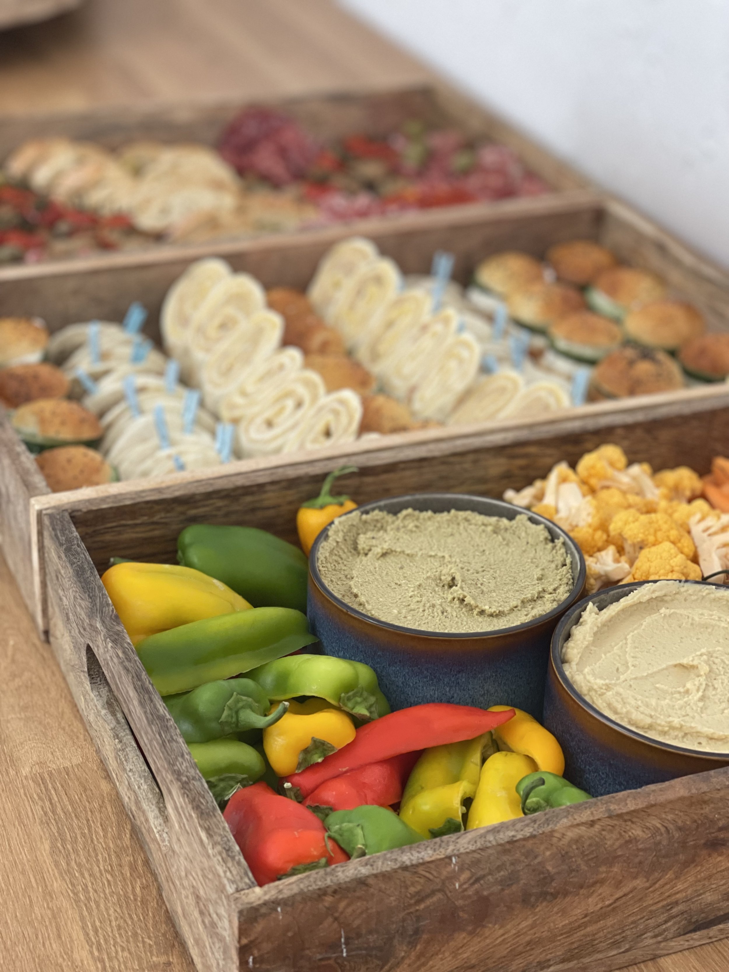 Plateau apéritif avec légumes colorés, houmous et mini-sandwichs roulés