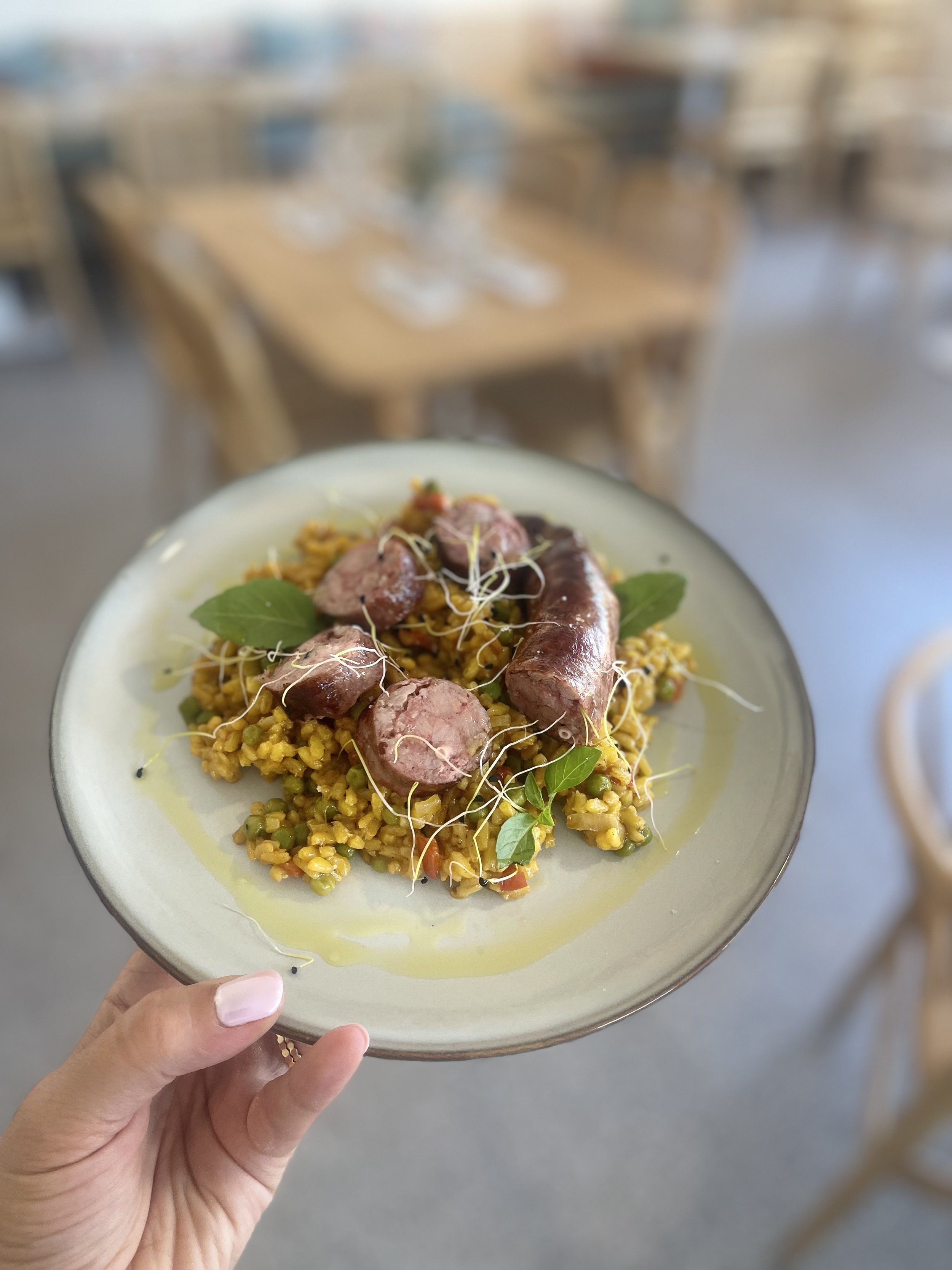 Assiette de riz sauté au curcuma avec saucisses grillées et herbes fraîches