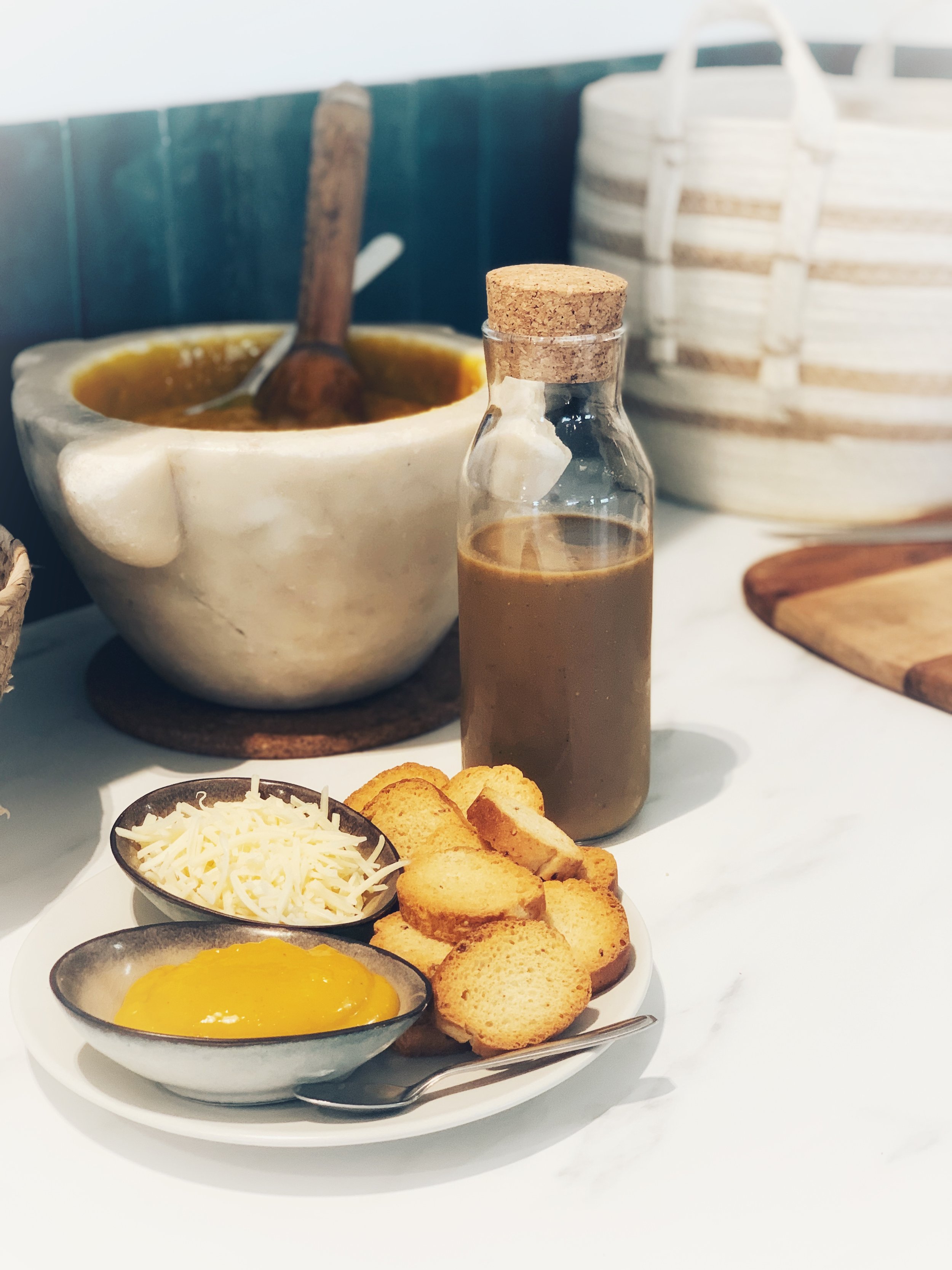 Soupe chaude avec croûtons, fromage râpé et sauce moutarde sur table en marbre